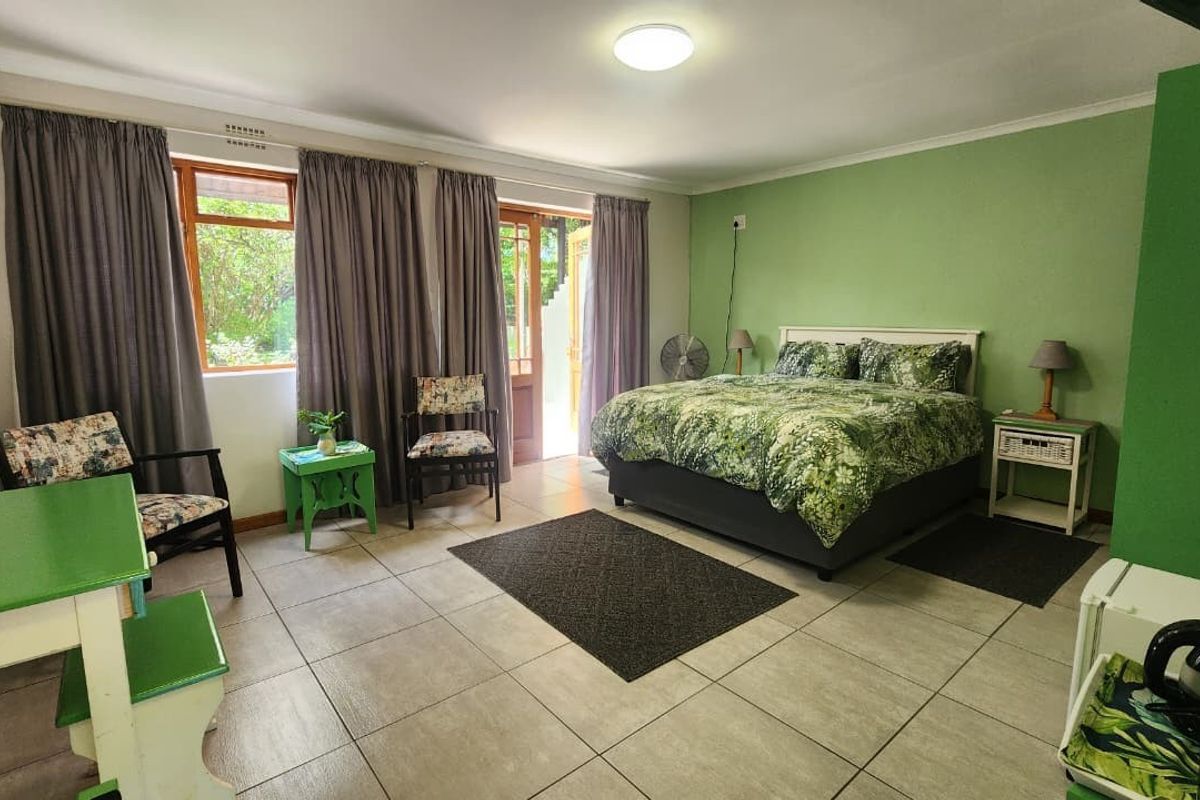 Spacious bedroom featuring tiled flooring, large windows, and direct access to the outdoors through a glass sliding door.