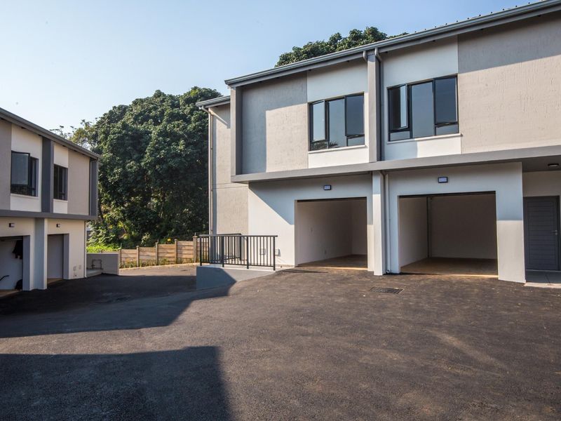 Modern apartment complex exterior featuring a paved driveway and double garage access with contemporary architectural finishes.