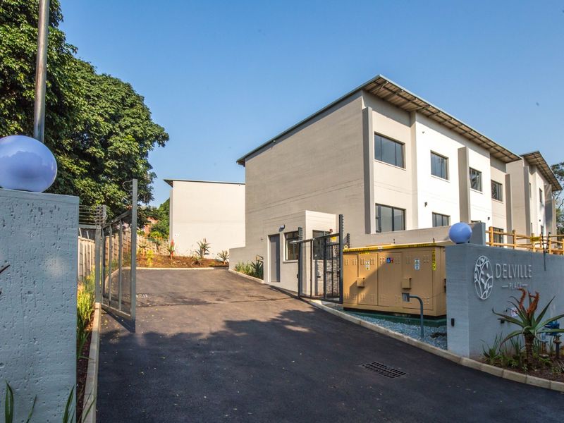 The entrance to Delville Place apartment complex, featuring a paved driveway, secure gated access, and modern exterior building finishes.