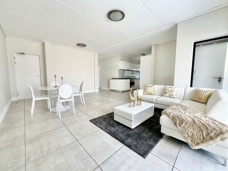 Spacious open-plan living and dining area featuring neutral tiled flooring and a modern kitchen with built-in cabinetry and integrated appliances.