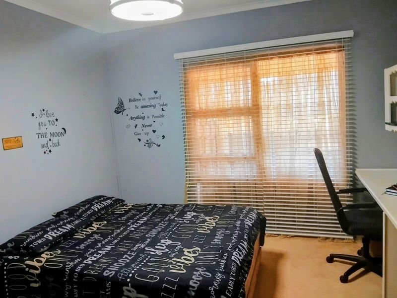 A bedroom featuring a built-in desk, venetian blinds, and a ceiling light fixture.