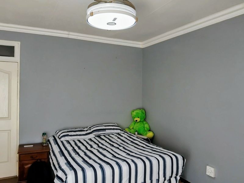 A bedroom featuring grey walls, decorative ceiling cornicing, and a central flush mount light fixture.