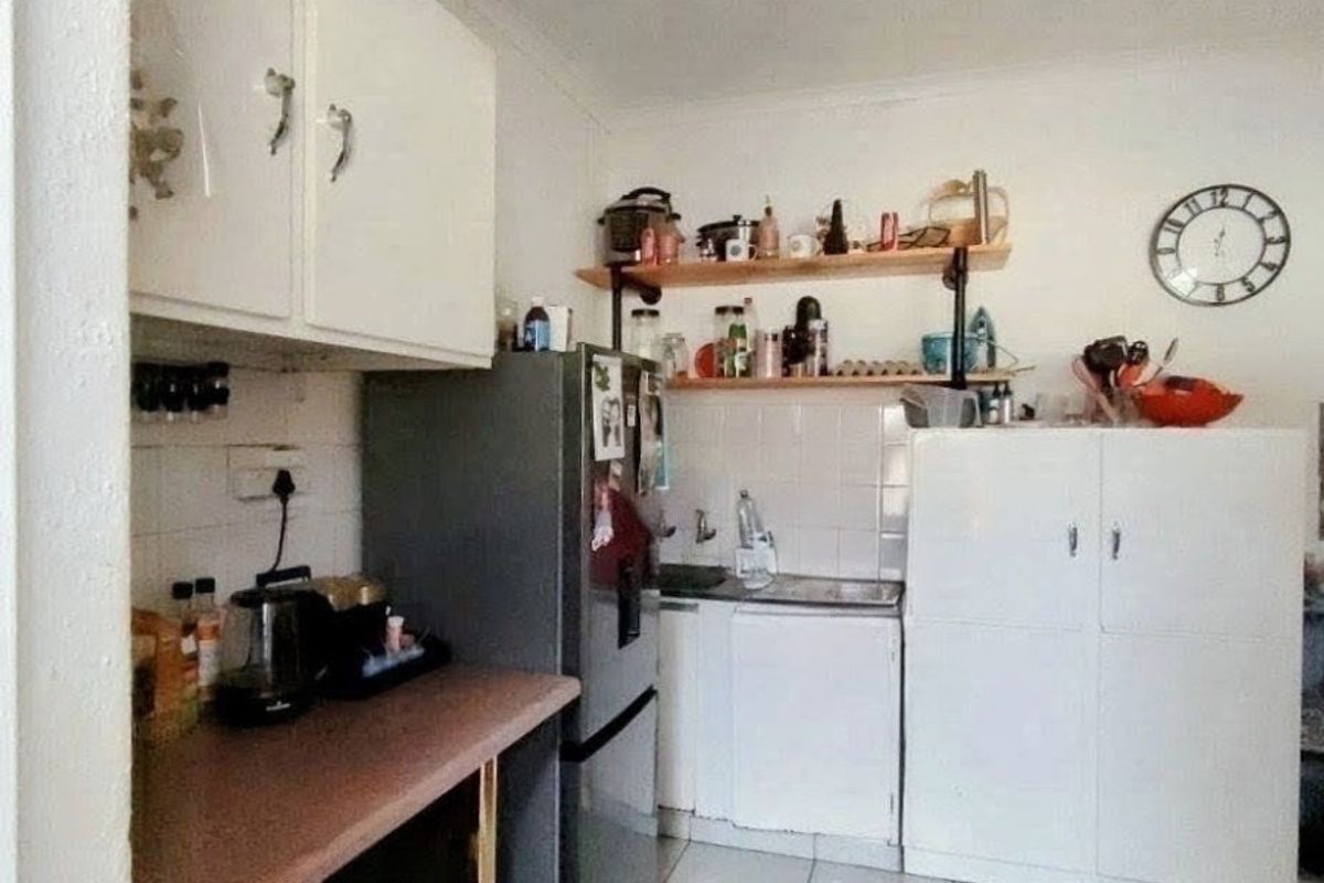 A compact kitchen featuring tiled flooring, wall-mounted cabinetry, open shelving, and a tiled splashback area.