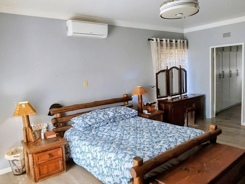 A spacious bedroom featuring a split-system air conditioner, built-in cupboards, and neutral wall finishes.
