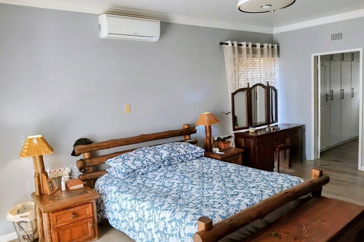 A spacious bedroom featuring a split-system air conditioner, built-in cupboards, and neutral wall finishes.