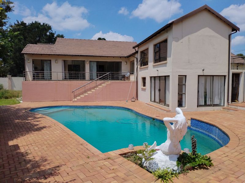Rear exterior view featuring a swimming pool, paved patio area, and direct access to the house via sliding glass doors and an external staircase.