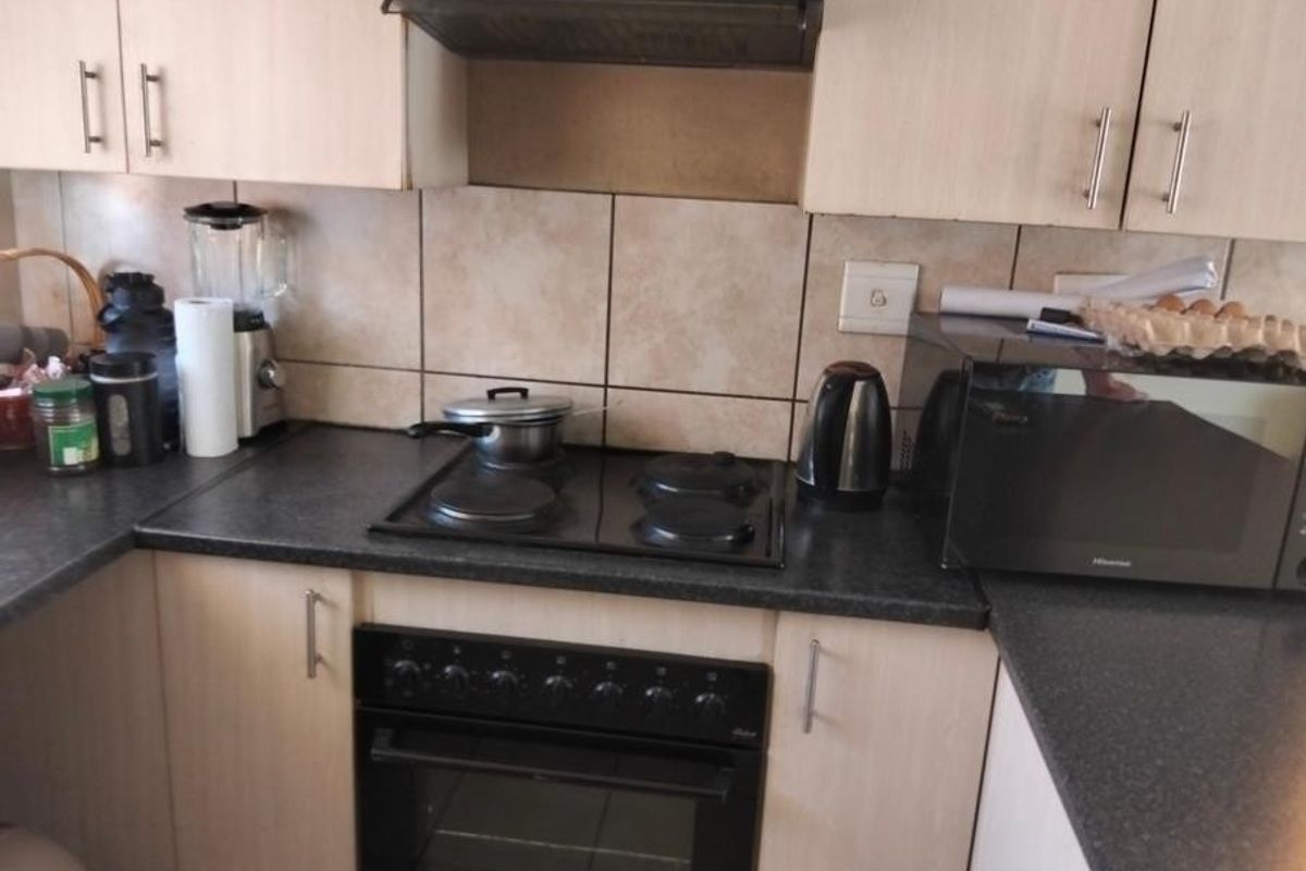 A functional kitchen area featuring built-in cabinetry, a tiled backsplash, and integrated cooking appliances including an oven and hob.