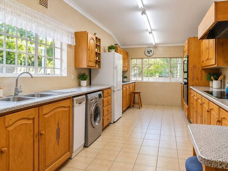 A functional kitchen featuring wooden cabinetry, laminate countertops, tiled splashbacks, and integrated appliances, offering a classic layout with ample natural light.