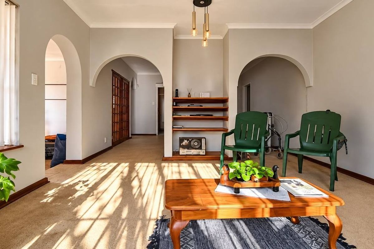 A bright living room featuring distinctive arched doorways, built-in shelving, and neutral wall finishes, offering a versatile space with natural light.