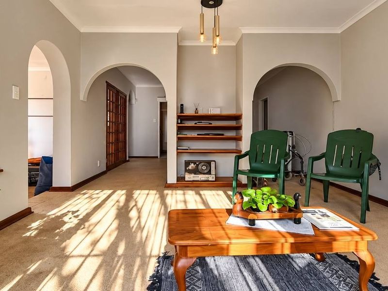 A bright living room featuring distinctive arched doorways, built-in shelving, and neutral wall finishes, offering a versatile space with natural light.