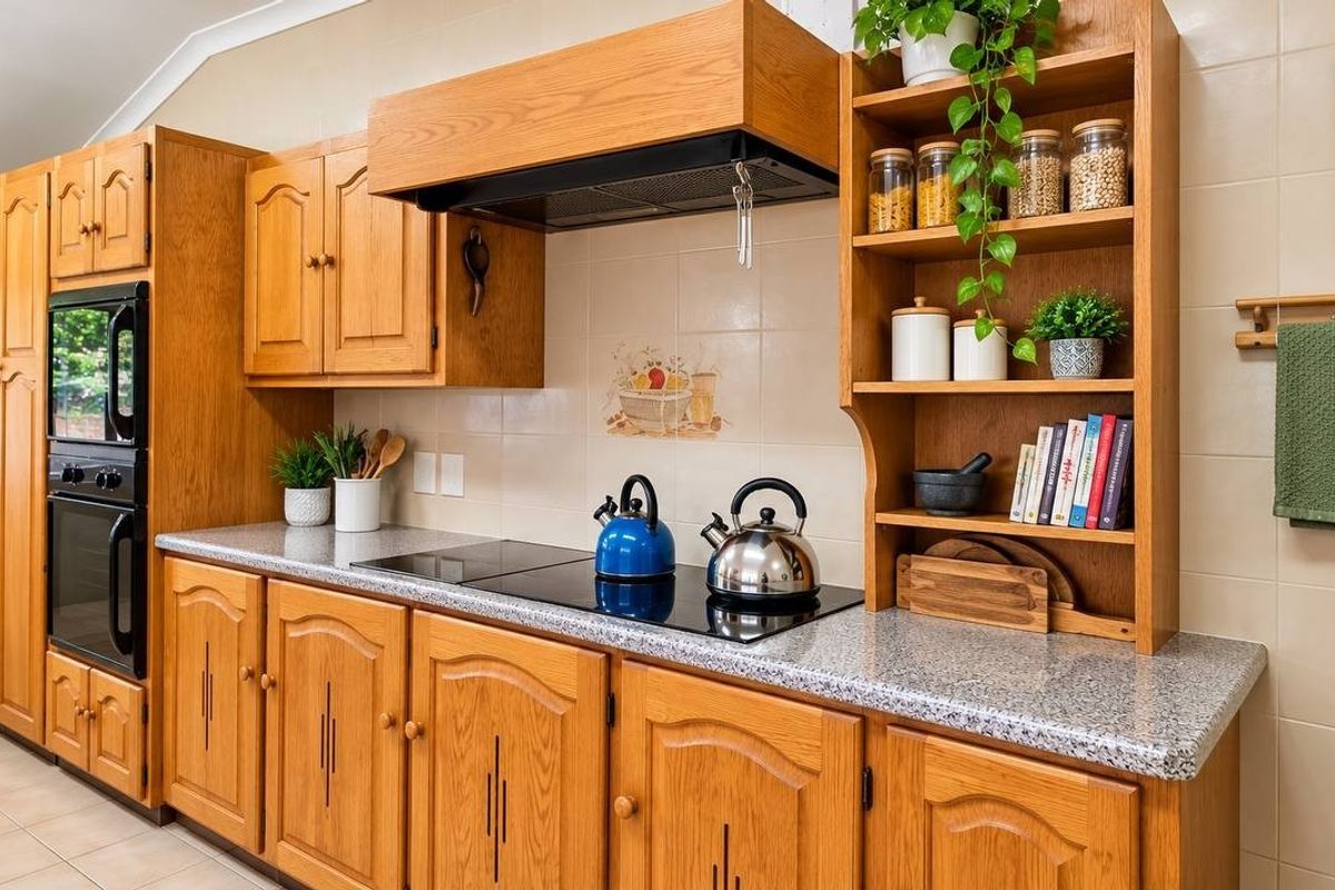 A functional kitchen featuring traditional oak cabinetry, granite-look laminate countertops, a built-in double oven, and an electric hob with an integrated extractor fan.