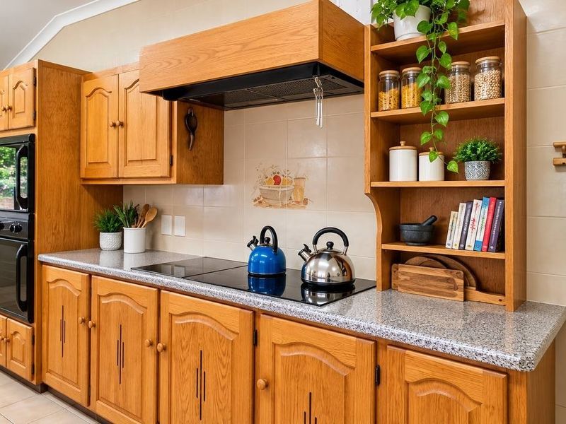 A functional kitchen featuring traditional oak cabinetry, granite-look laminate countertops, a built-in double oven, and an electric hob with an integrated extractor fan.