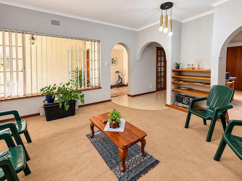 A spacious living room featuring classic archways, built-in shelving, and neutral wall finishes, offering a versatile layout with good natural light.