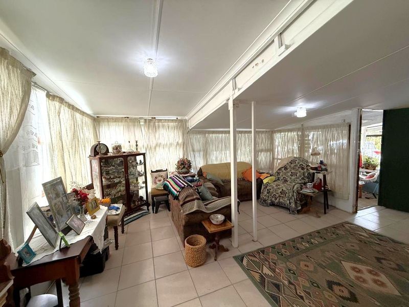 A spacious living area featuring tiled flooring and structural support columns, offering a versatile layout with ample natural light.