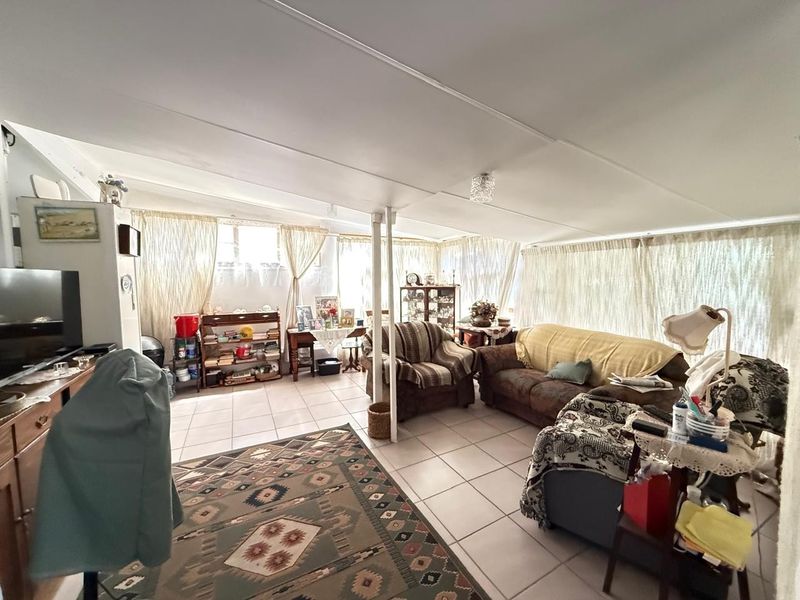 A spacious living area featuring tiled flooring, a sloped ceiling, and a central support column, offering a functional layout with ample natural light.