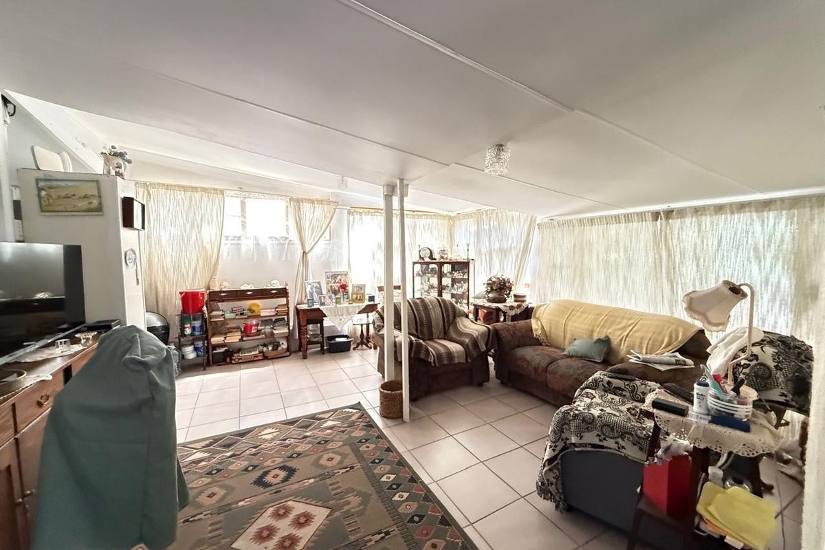A spacious living area featuring tiled flooring, a sloped ceiling, and a central support column, offering a functional layout with ample natural light.