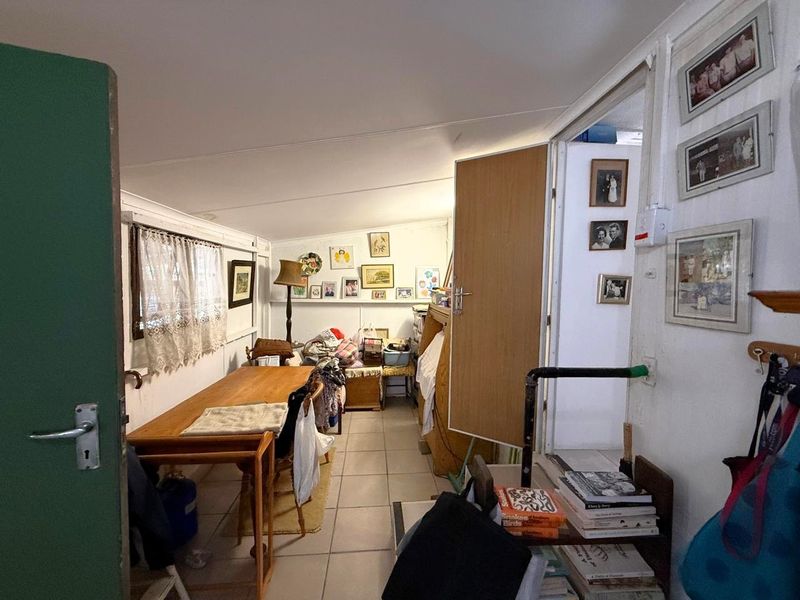 A compact living area featuring tiled flooring and an exposed plumbing pipe, requiring cosmetic updates to improve the overall aesthetic and functionality.