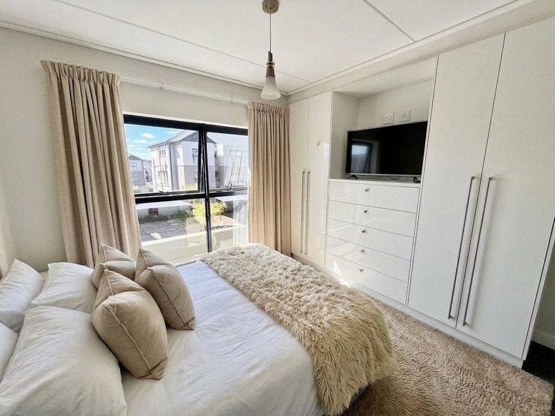 A well-maintained bedroom featuring built-in cupboards with integrated storage and a large window providing natural light.