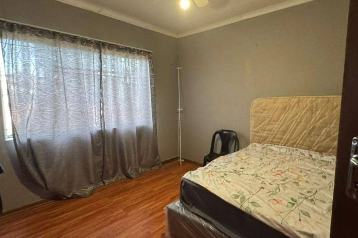 A standard bedroom featuring laminate flooring, a ceiling fan, and neutral wall finishes.