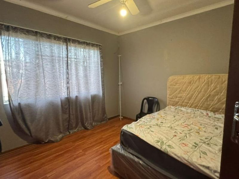 A standard bedroom featuring laminate flooring, a ceiling fan, and neutral wall finishes.