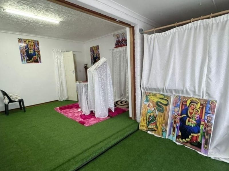 An interior space featuring textured ceilings and artificial turf flooring, currently utilized for religious purposes.