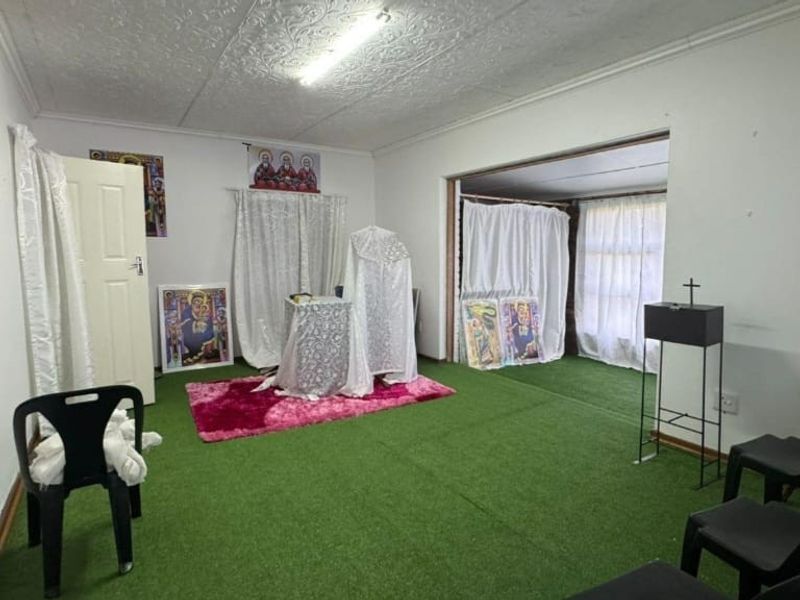 An interior living space featuring a textured ceiling and artificial turf flooring, currently utilized as a multi-purpose area.