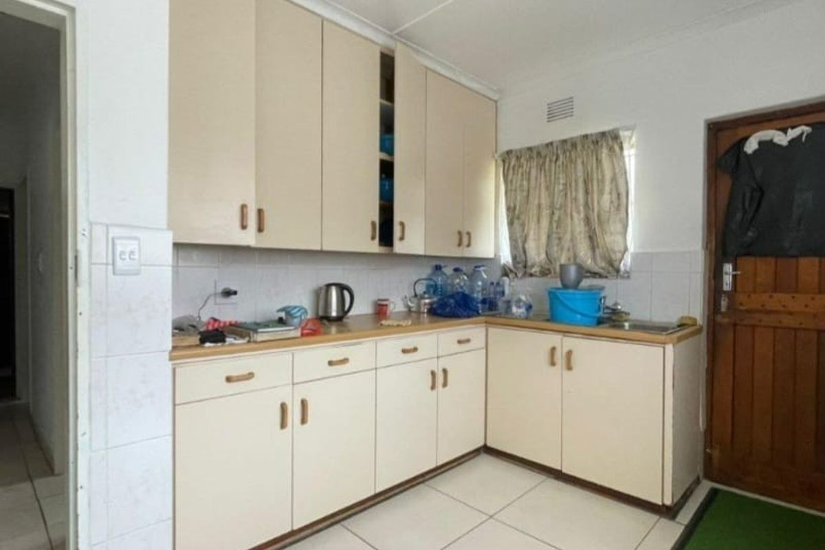 A functional kitchen featuring built-in cabinetry, laminate countertops, and tiled flooring, offering a practical layout with potential for modernization.