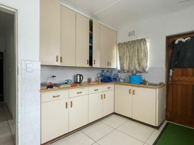 A functional kitchen featuring built-in cabinetry, laminate countertops, and tiled flooring, offering a practical layout with potential for modernization.