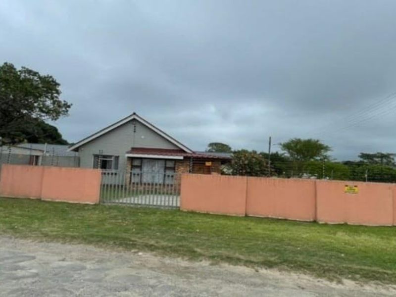Front view of a single-story house featuring a tiled roof, brick facade, and a secure perimeter wall with electric fencing and a metal gate.