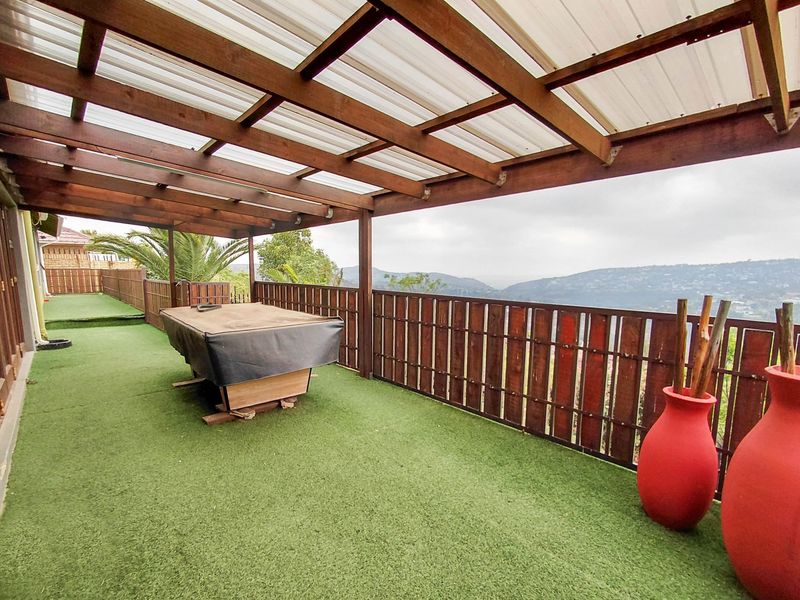 Covered outdoor patio featuring a timber pergola structure, artificial turf flooring, and a timber balustrade with scenic mountain views.