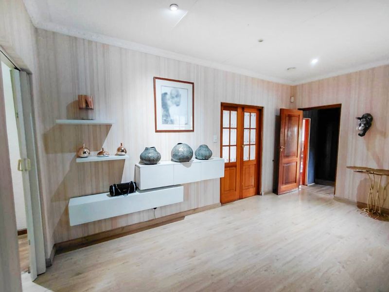 A well-maintained living area featuring laminate flooring, recessed downlights, decorative coving, and built-in floating cabinetry with integrated shelving.