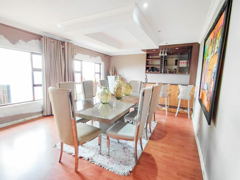 Dining room featuring laminate flooring, a built-in bar area, and a recessed ceiling, with some wall finishing required around the window frames.