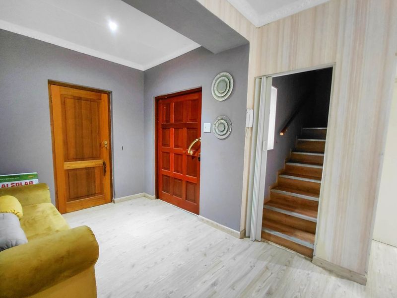Entrance foyer featuring laminate flooring, wooden doors, and an internal staircase leading to the upper level.