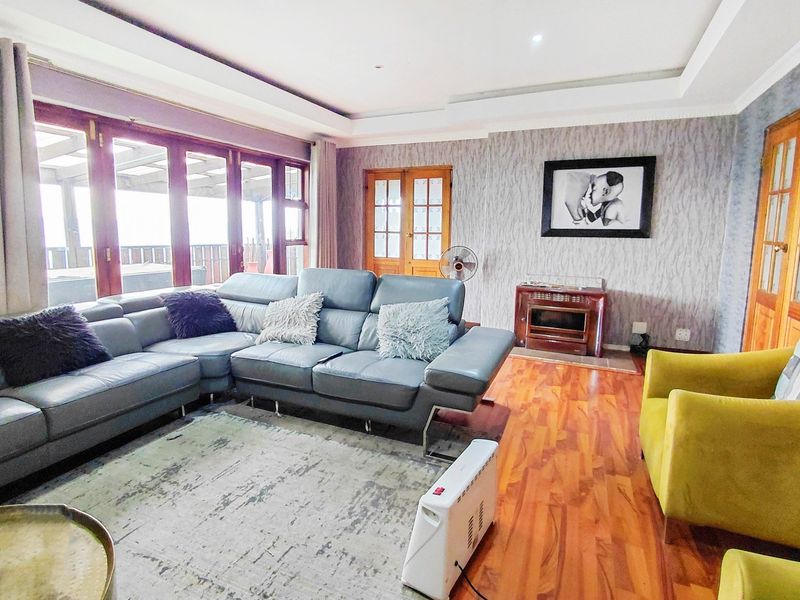 Spacious living room featuring warm wooden flooring, a built-in fireplace, and large timber-framed glass sliding doors providing access to the outdoor area.
