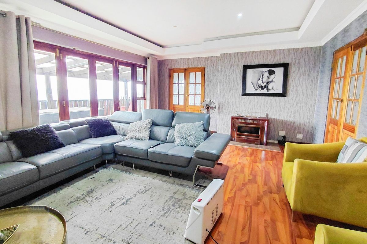 Spacious living room featuring warm wooden flooring, a built-in fireplace, and large timber-framed glass sliding doors providing access to the outdoor area.