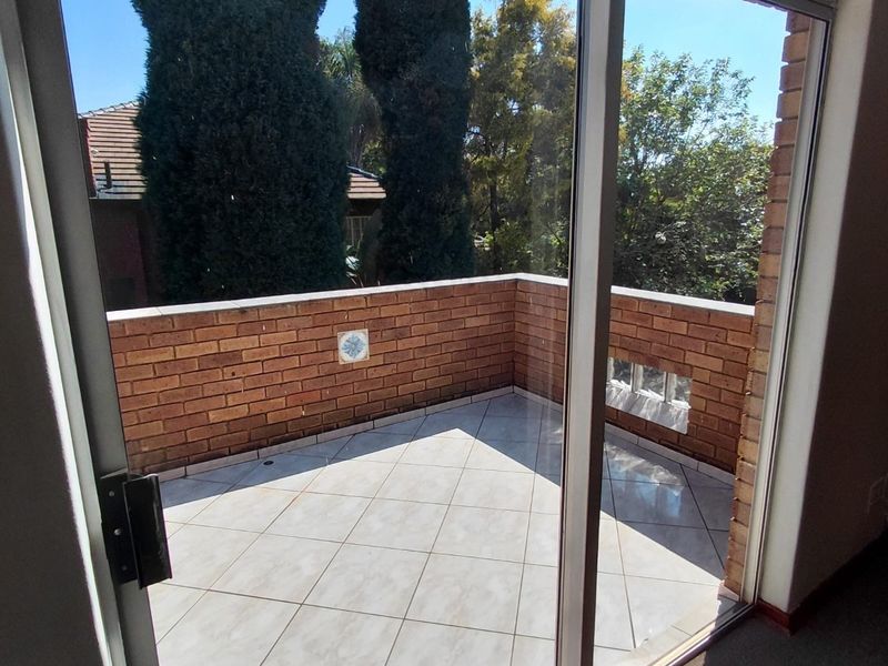 A private balcony featuring tiled flooring and a brick balustrade, accessible through a sliding glass door.