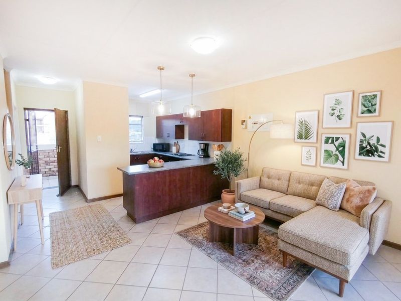 An open-plan living and kitchen area featuring tiled flooring, dark wood cabinetry, and a breakfast bar, creating a functional and cohesive living space.