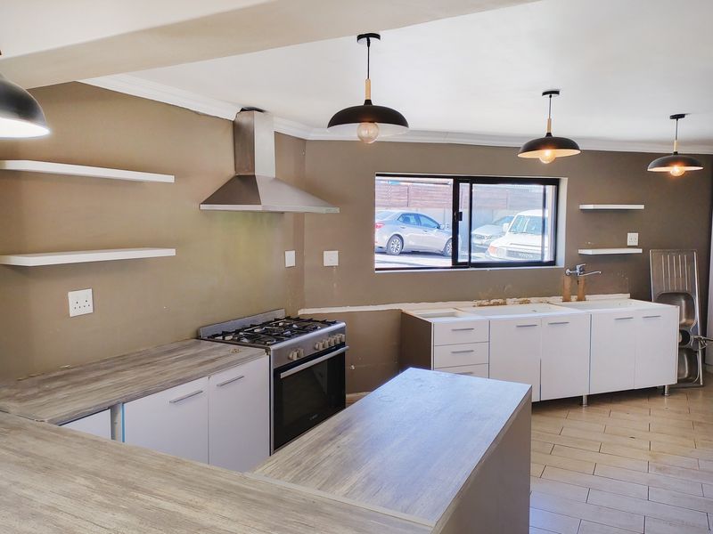 A partially renovated kitchen featuring a gas stove, stainless steel extractor, and modern cabinetry, currently awaiting final installation and finishing touches.