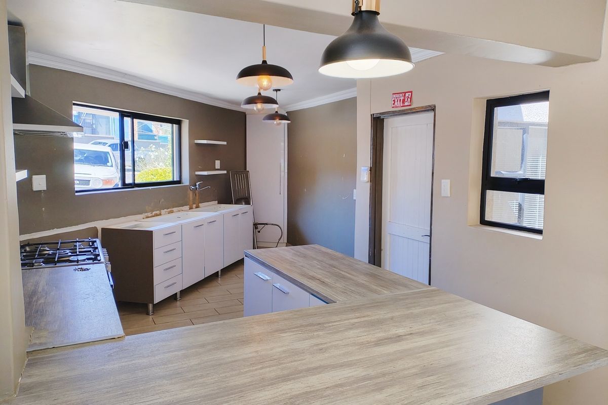A spacious, partially finished kitchen featuring a gas hob, ample cabinetry, and a large breakfast bar, ready for final touches and personal styling.