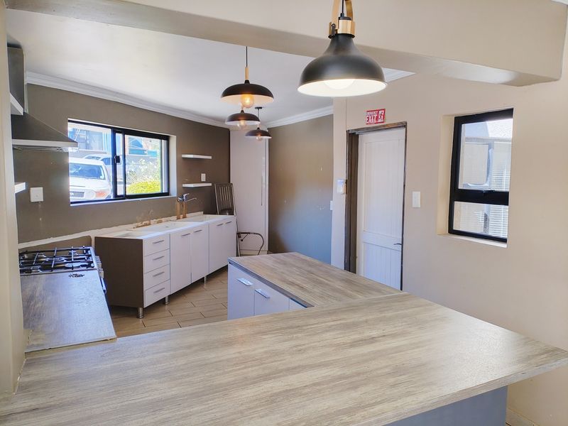 A spacious, partially finished kitchen featuring a gas hob, ample cabinetry, and a large breakfast bar, ready for final touches and personal styling.