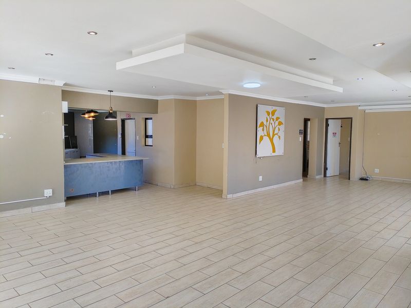 Spacious open-plan living area featuring tiled flooring, recessed ceiling details with downlights, and a built-in breakfast counter, offering a versatile layout.