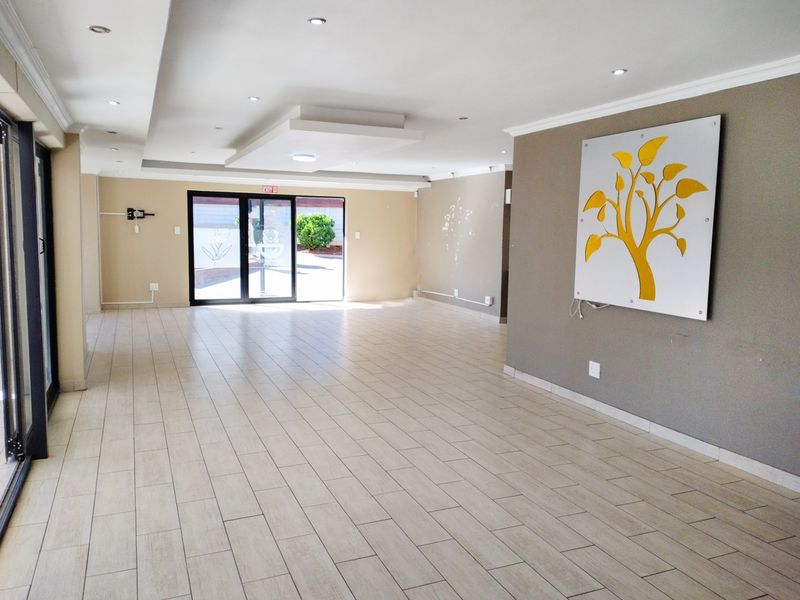 A spacious, empty living area featuring modern tiled flooring, recessed ceiling lighting, and large sliding glass doors providing access to the exterior.