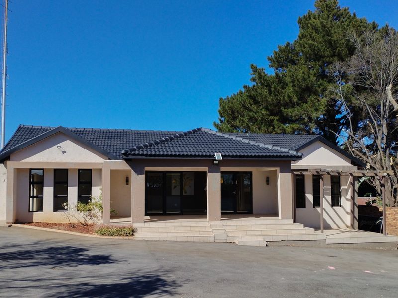 Front elevation of a well-maintained single-story house featuring a tiled roof, covered patio entrance, and paved driveway area.