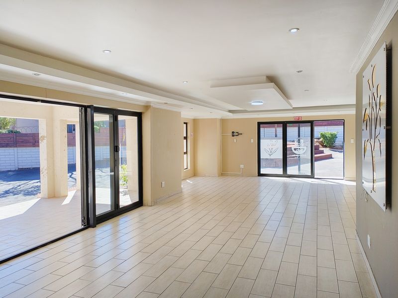 Spacious, light-filled living area featuring modern tiled flooring, recessed ceiling lighting, and large aluminium stacker doors providing seamless access to the outdoor patio.