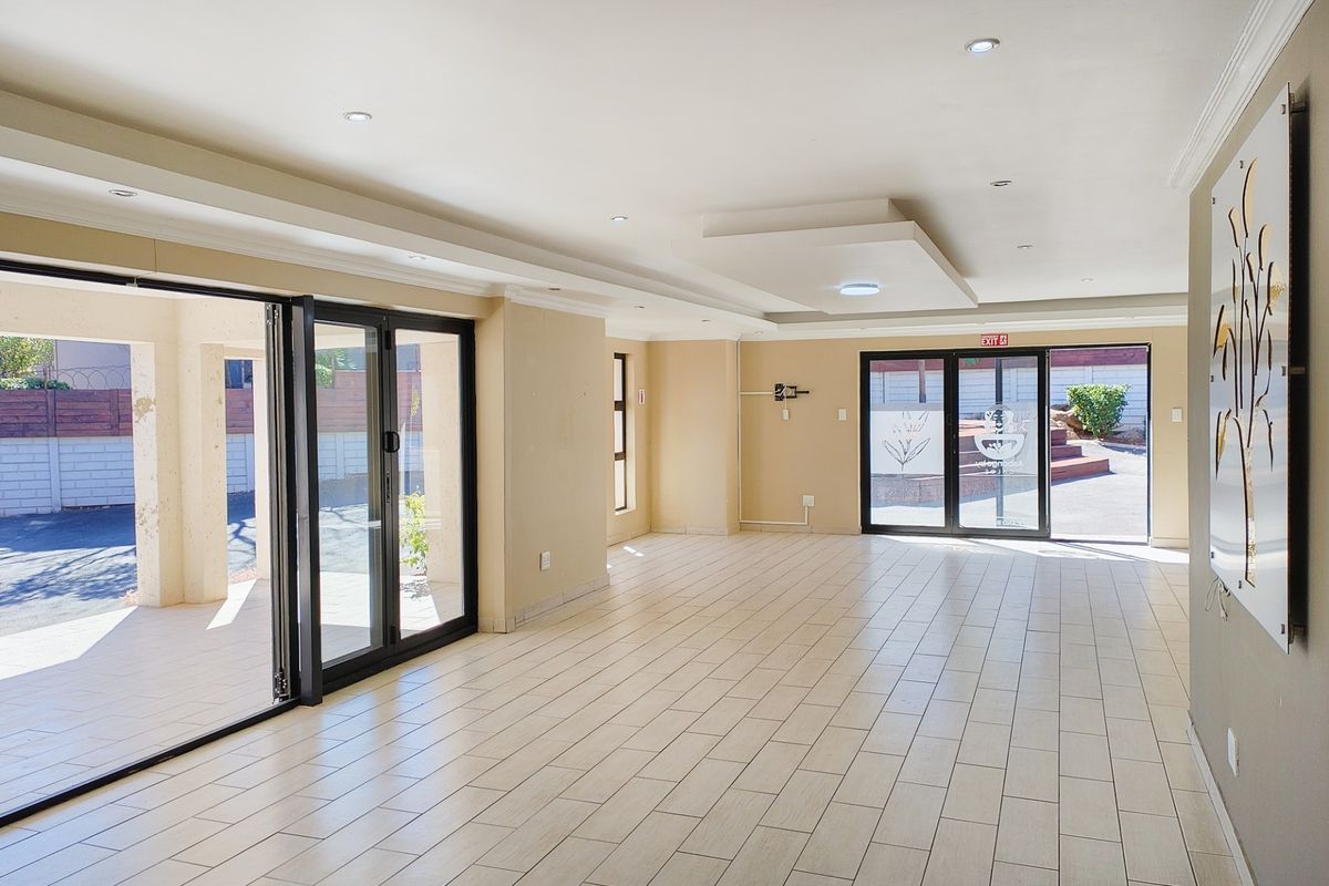Spacious, light-filled living area featuring modern tiled flooring, recessed ceiling lighting, and large aluminium stacker doors providing seamless access to the outdoor patio.