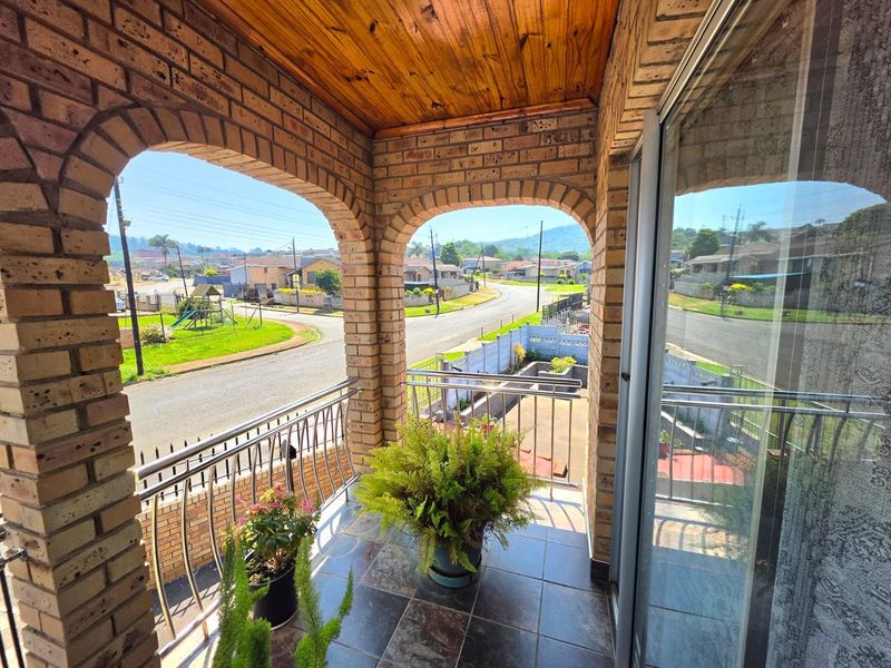 A covered balcony featuring brick arches, a timber ceiling, and tiled flooring, offering an elevated view of the surrounding neighborhood.