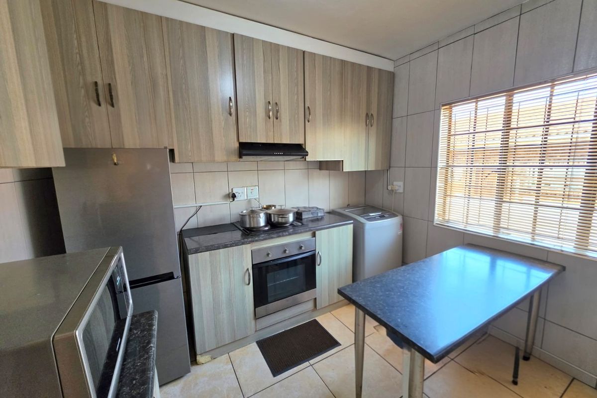 A functional kitchen featuring wood-look cabinetry, built-in oven with extractor fan, tiled backsplash, and tiled flooring, offering a practical layout for daily use.