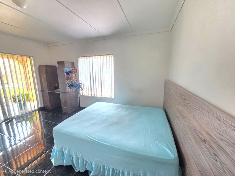 A bedroom featuring dark tiled flooring, a built-in desk unit, and vertical blinds, offering a functional space with neutral wall finishes.