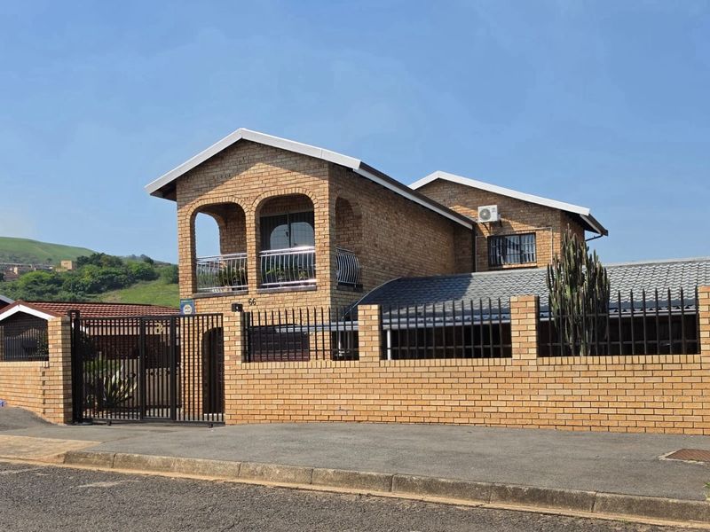 A well-maintained double-story face brick house featuring an arched balcony, secure perimeter walling, and gated entrance.