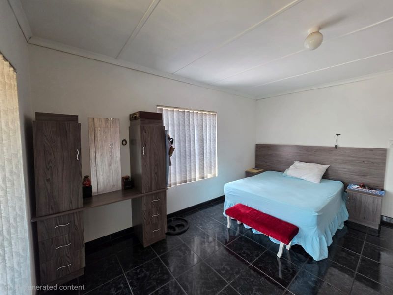 A bedroom featuring dark tiled flooring, built-in cupboards with a vanity section, and a built-in headboard with matching bedside pedestals.